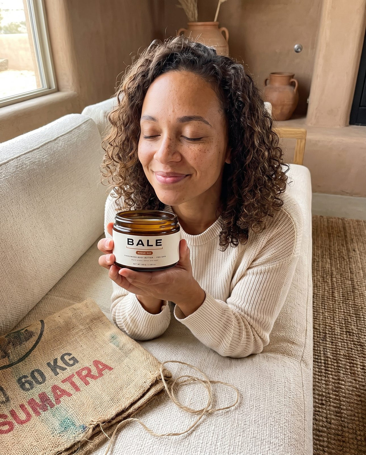 Woman smelling an open jar of Rogue 540 body butter with her eyes closed