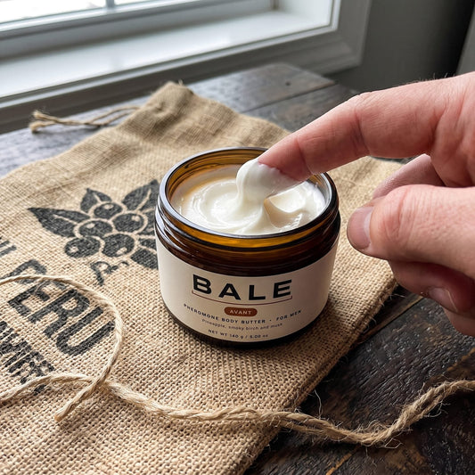 A finger taking a scoop of whipped Bale Avant body butter from the jar, on a piece of coffee sack