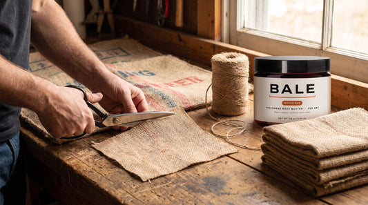 Hands cutting a square from a printed coffee sack with scissors beside twine and a Bale jar