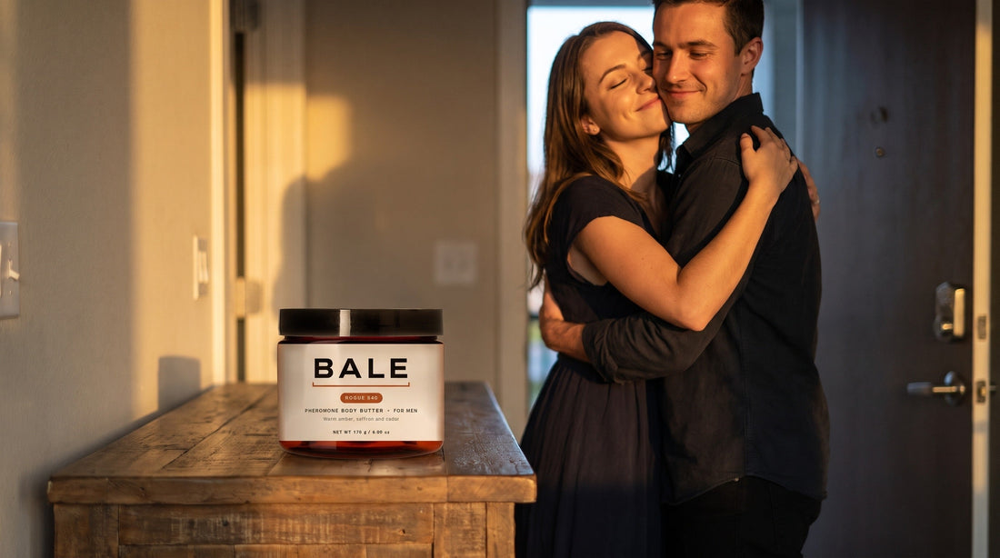 A woman hugging a man at an apartment door at golden hour with a Bale jar on the table