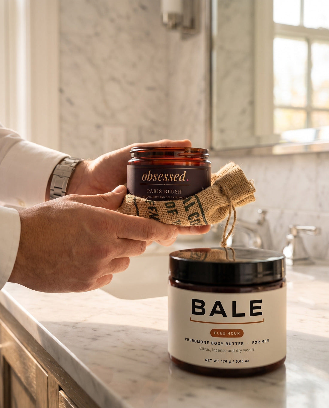 A man's hands holding obsessed Paris Blush wrapped in coffee sack beside his Bale Bleu Hour jar