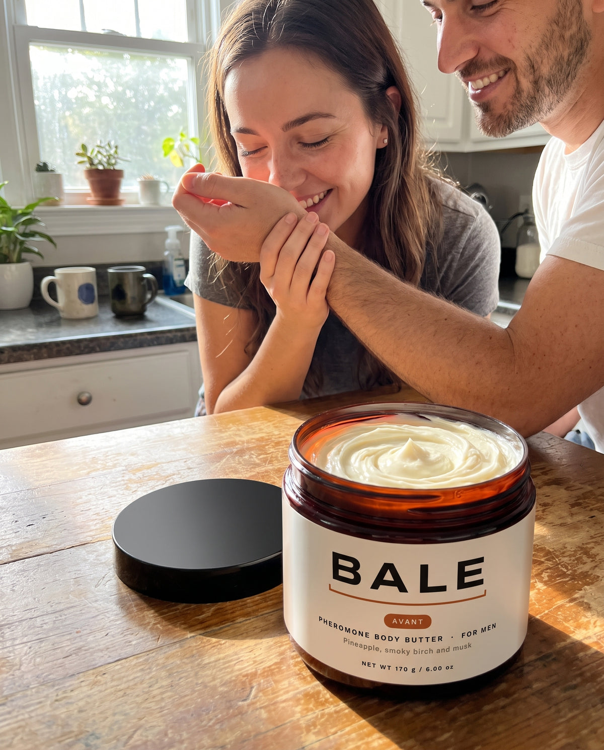 She smells his wrist in the kitchen, open Avant jar on the table