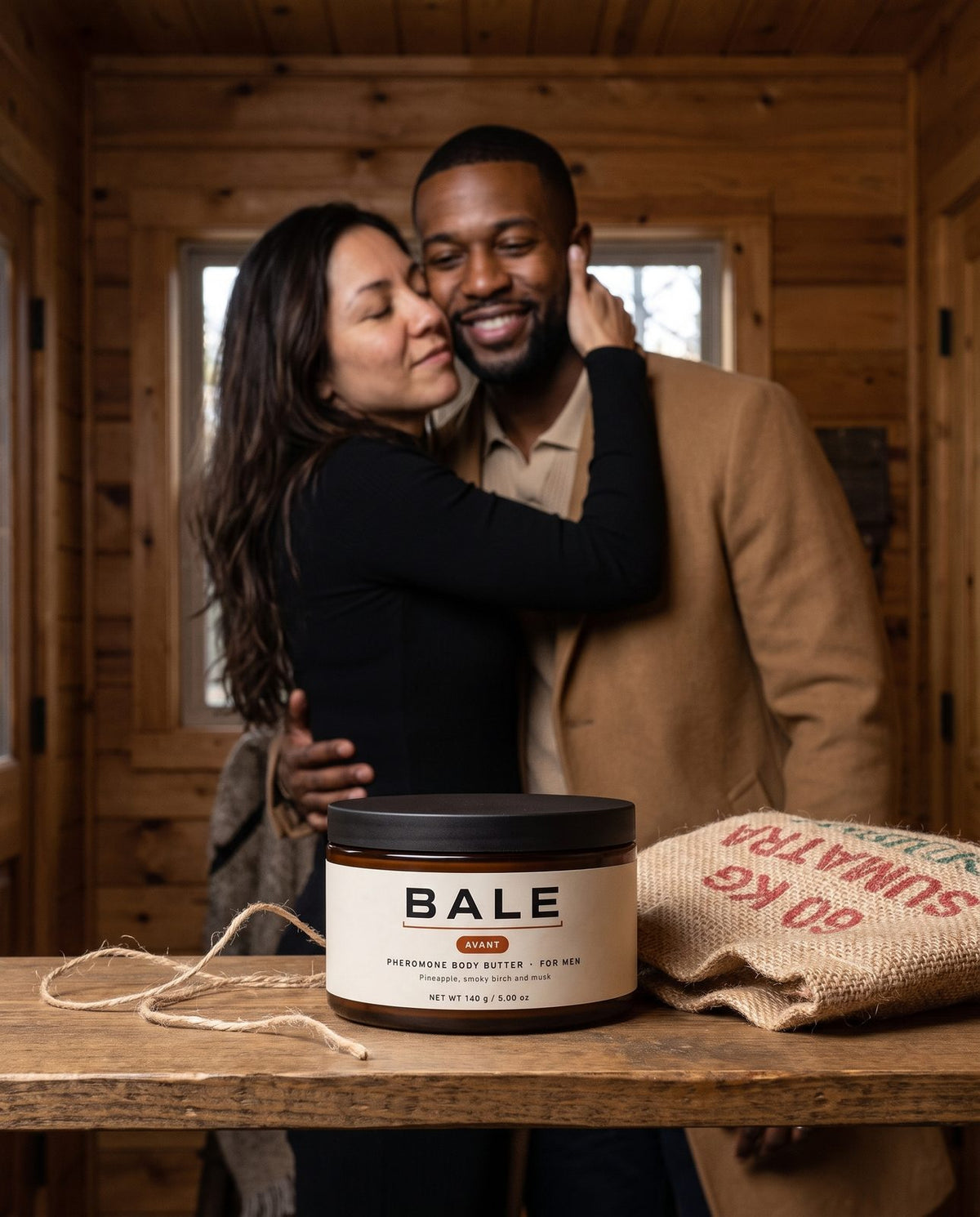 Couple hugging at the front door, Avant jar and coffee sack wrap on the shelf