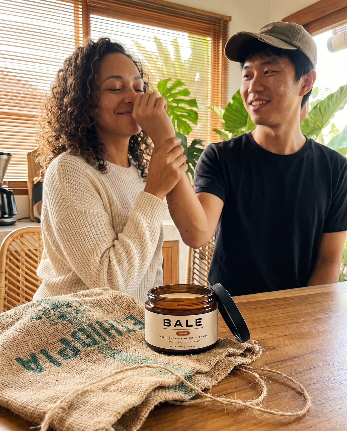 She smells his wrist in the kitchen, open Avant jar on the table