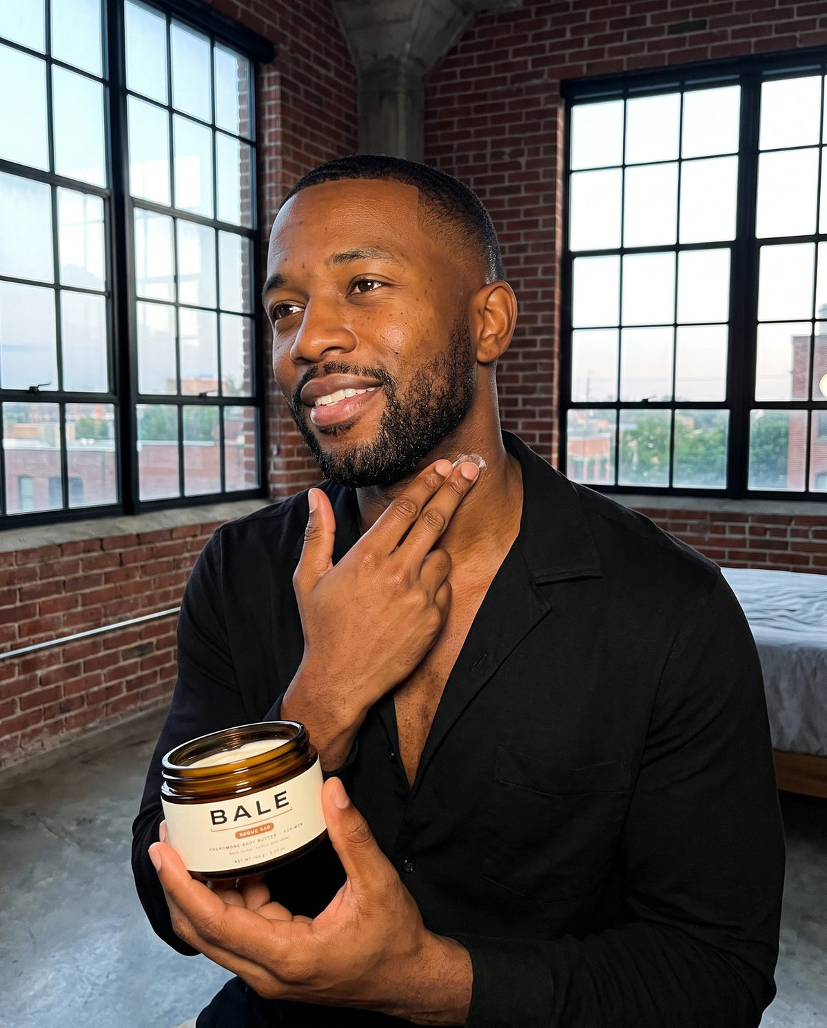 Man pressing body butter onto his neck before a date, holding the Rogue 540 jar