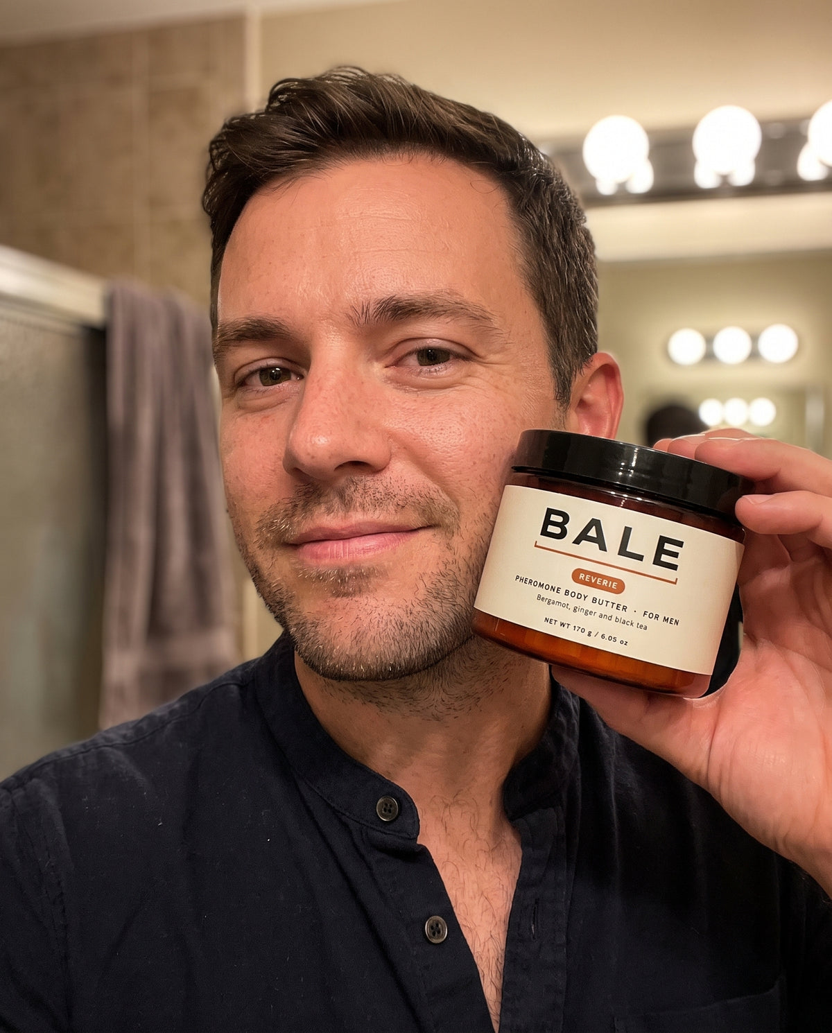 Man holding a jar of Reverie body butter while getting ready in the evening