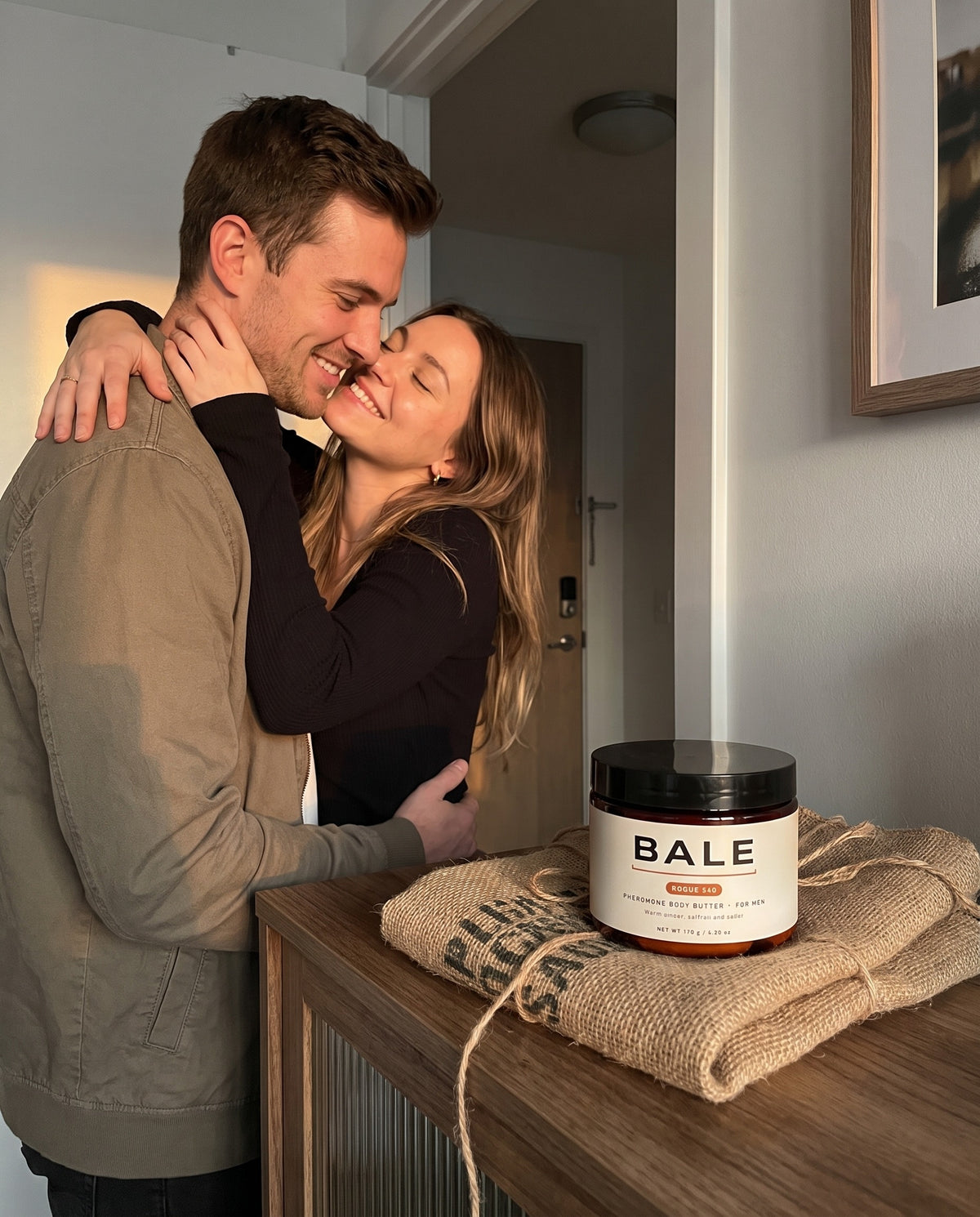 Couple hugging at the front door, Rogue 540 jar on a coffee sack wrap beside them