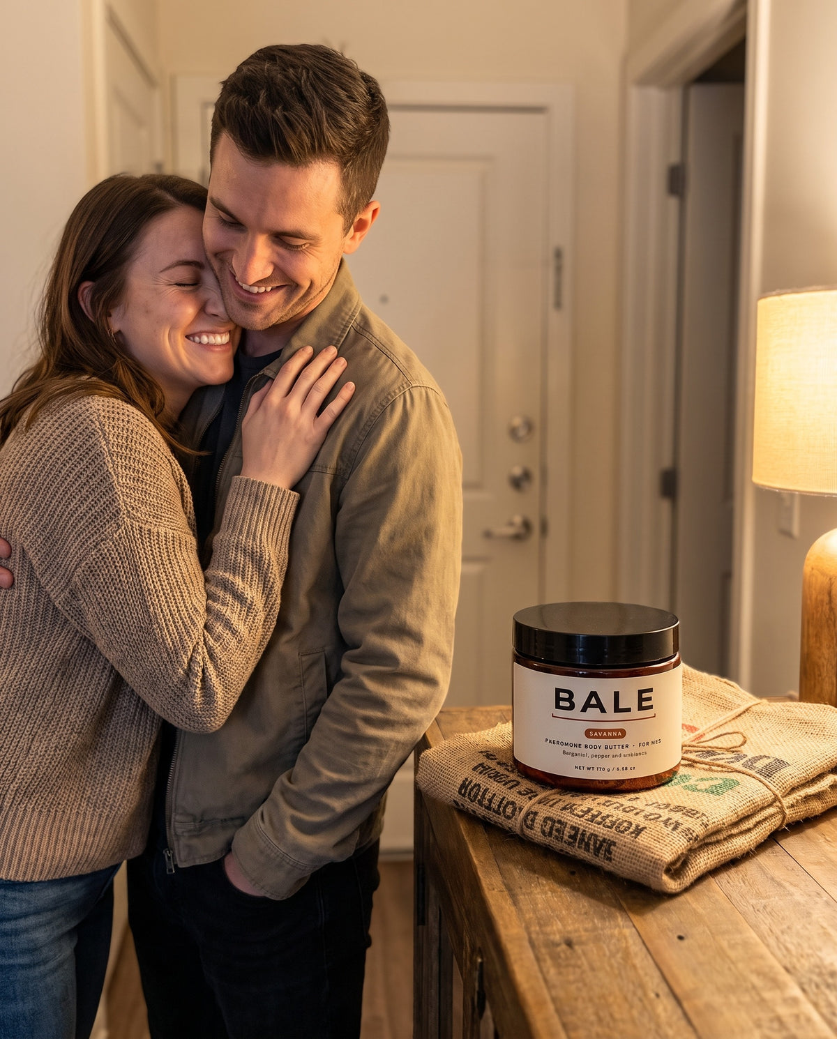 Couple hugging at the front door, Savanna jar on a coffee sack wrap beside them